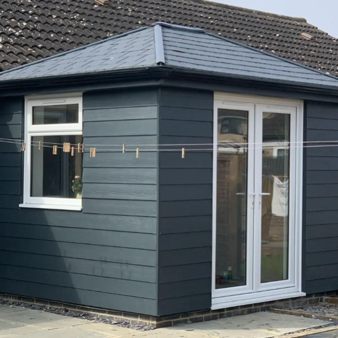 Energy-efficient HUP! home extension featuring dark composite cladding, white uPVC French doors, and a tiled warm roof. By Norfolk Exterior Solutions